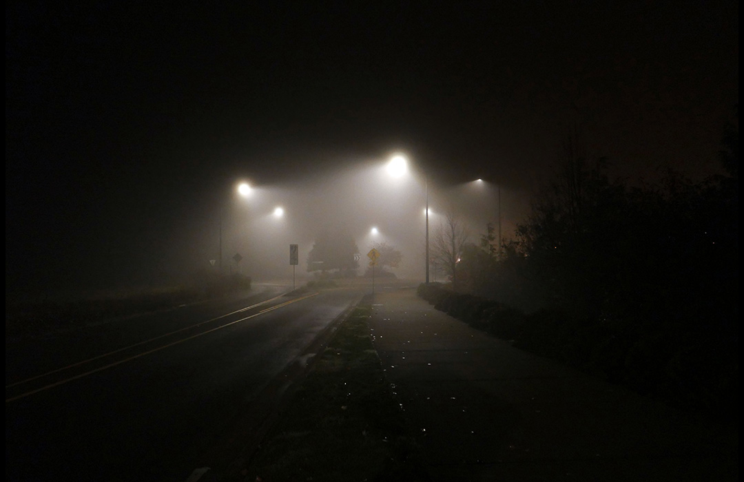 A street at night with fog illuminated by the street lights